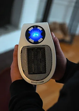 Hand holding the Toasty Heater to show its compact size, with a blue digital display